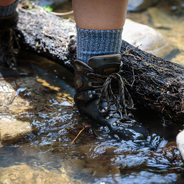 Close up of a trampers boot as they cross a river